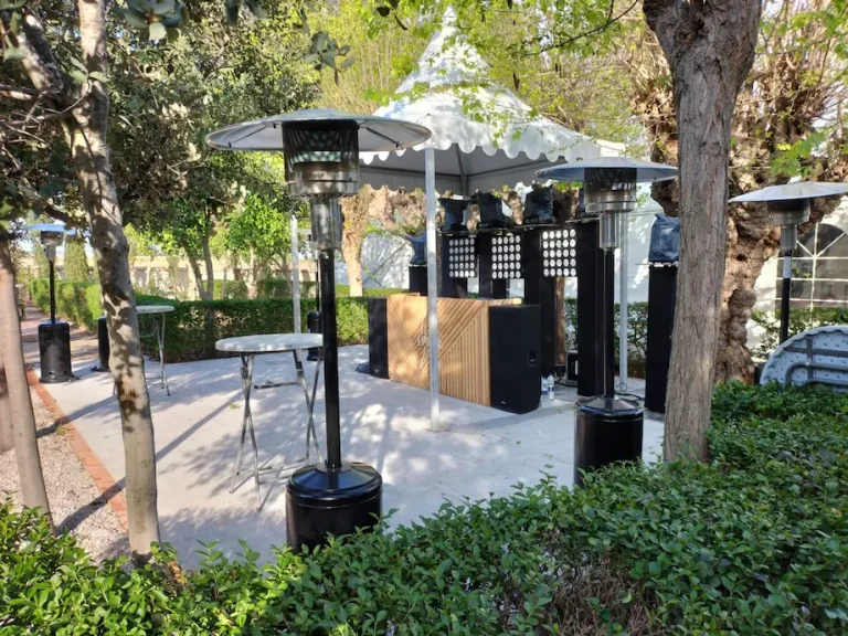 Estufa de gas butano en un gazebo con mesa y sillas en un jardín.