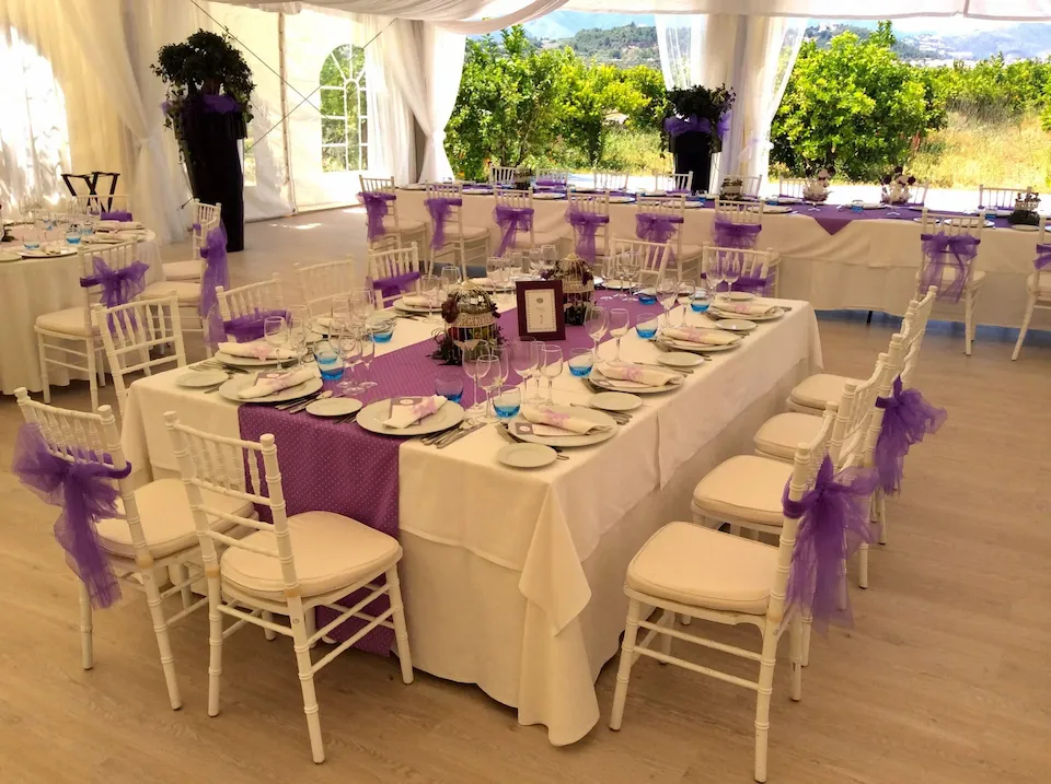 Recepción de boda con manteles morados y blancos, decoraciones elegantes y mesas dispuestas para los invitados.