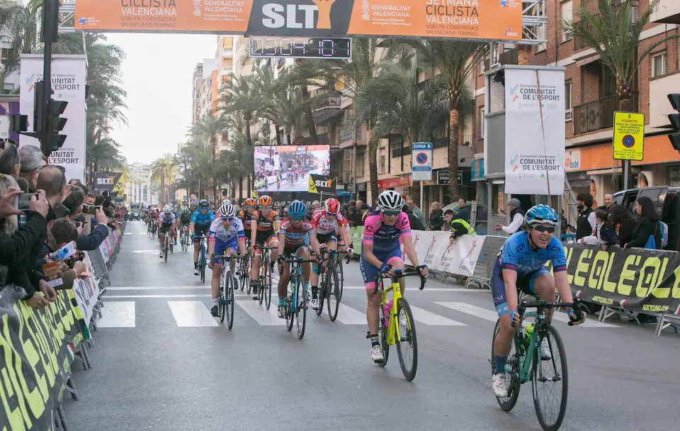 Grupo de ciclistas compitiendo en una carrera frente a una multitud animada en la calle.