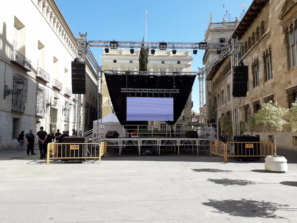 Escenario de feria ubicado en una plaza urbana, con luces y adornos que crean un ambiente festivo.