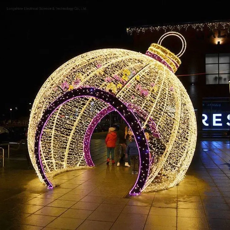 Gran bola navideña iluminada con personas reunidas a su alrededor, creando un ambiente festivo.