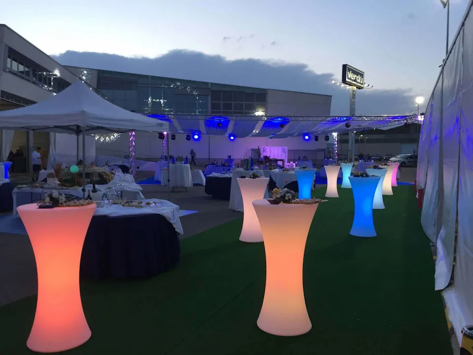 Celebración con mesas y sillas de diversos colores, creando un ambiente vibrante y animado.