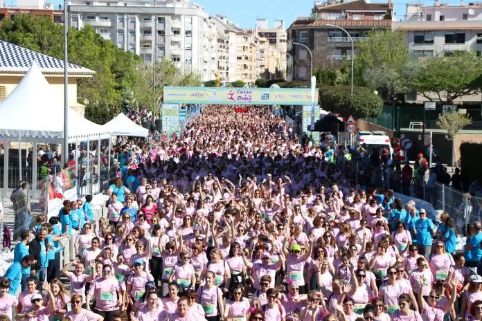 Multitud de corredores con camisetas rosas participando en una carrera deportiva al aire libre.