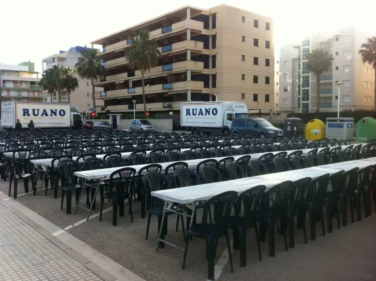 Mesas y sillas alineadas en un aparcamiento, creando un espacio para sentarse al aire libre.