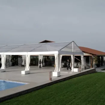 Vista de una amplia carpa blanca rodeada de césped y una piscina en el patio trasero.