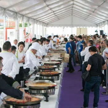 Un gran grupo de personas disfrutando de comida en un puesto de comida al aire libre.