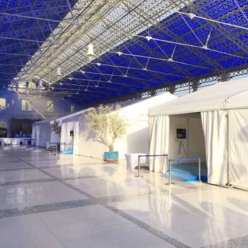 Gran carpa blanca con techo azul y paredes blancas, utilizada para eventos al aire libre.