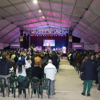 Un gran grupo de personas reunidas dentro de una carpa amplia, participando en un evento social.