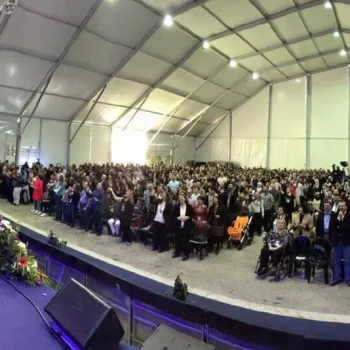 Multitud de personas reunidas en un gran toldo, creando un ambiente animado y social.