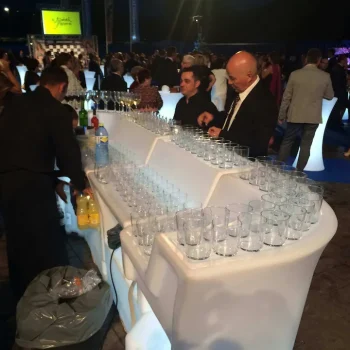 Barra de resina iluminada con luz LED, rodeada de personas con bebidas y copas en un ambiente social.