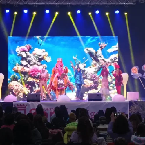 Escenario con artistas disfrazados durante un concierto infantil de Gisela Kids, entreteniendo a un público entusiasta.