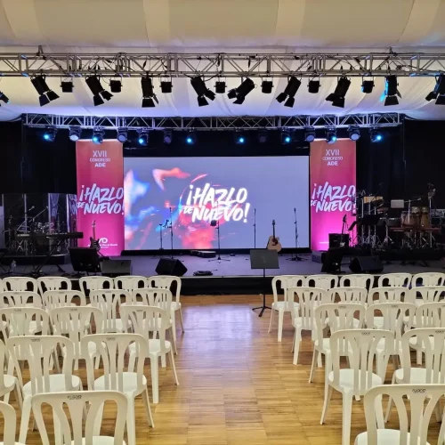Escenario amplio con sillas dispuestas y una pantalla de proyector para el Congreso ADE.