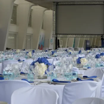 Mesa blanca grande dispuesta para un congreso, con sillas alrededor y decoraciones sutiles.