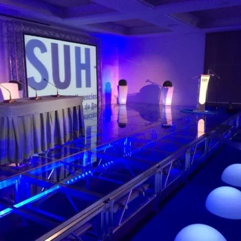 Escenario iluminado en azul con una gran pantalla al fondo, listo para una presentación o espectáculo.