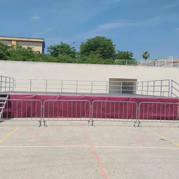 Escenario vestido en color morado, rodeado de vallas de aluminio.