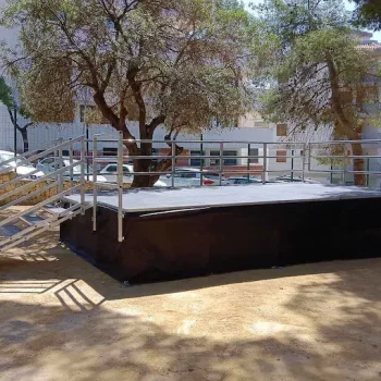 Escenario de aluminio con barandilla metálica y cubierta negra, listo para una presentación o evento.
