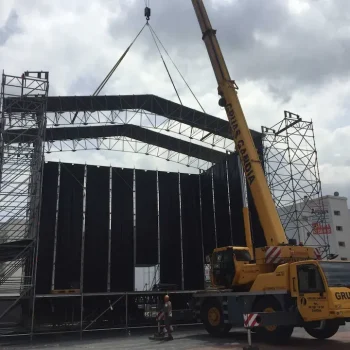 Escenario grande siendo levantado por una grúa para su transporte en un camión.