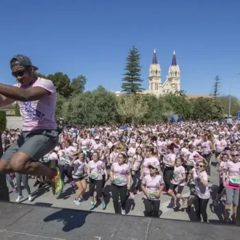 Hombre con camiseta rosa saltando en el escenario frente a una multitud animada.