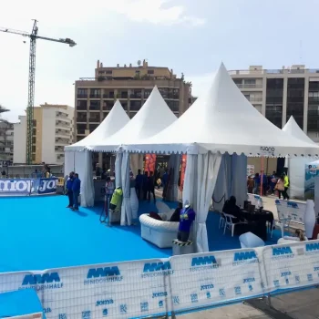 Carpa grande con alfombra azul, donde varias personas caminan y participan en un evento deportivo.