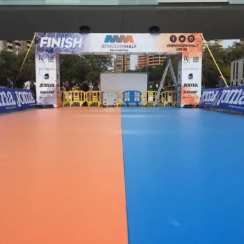 Tapete de competición azul y naranja dispuesto para una carrera en un evento deportivo.