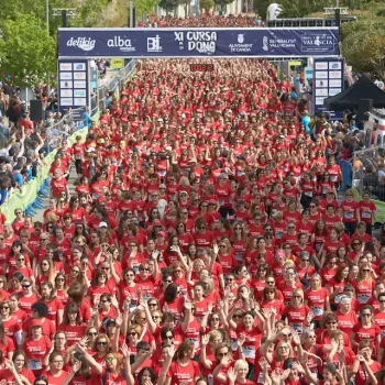 Multitud de corredores con camisetas rojas avanzando por una calle en un evento deportivo.