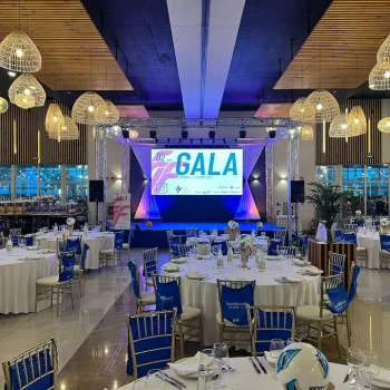 Vista de un salón con mesas azules y blancas, preparado para un evento deportivo.