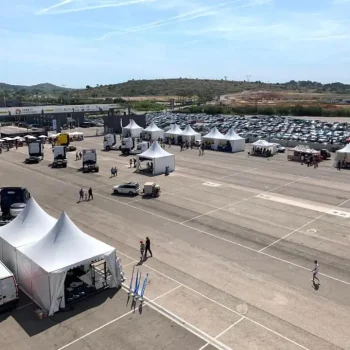 Gran estacionamiento lleno de coches y carpas, preparado para un evento deportivo al aire libre.