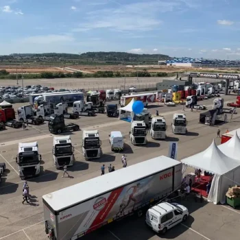 Varios camiones alineados en un aparcamiento, listos para un evento deportivo.