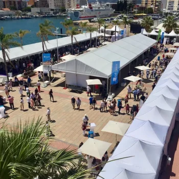 Feria en el Grau de Gandía con carpas y numerosas personas disfrutando del evento al aire libre.