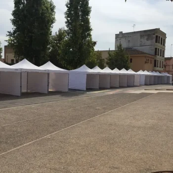 Fila de carpas blancas alineadas en una calle de la ciudad durante una feria.