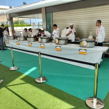 Grupo de chefs preparando alimentos en una mesa durante una feria gastronómica.