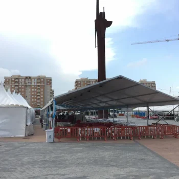 Carpa con mesas y sillas dispuestas frente a un edificio durante una feria.