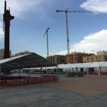 Gran carpa blanca en una feria, rodeada de actividades y visitantes disfrutando del evento.