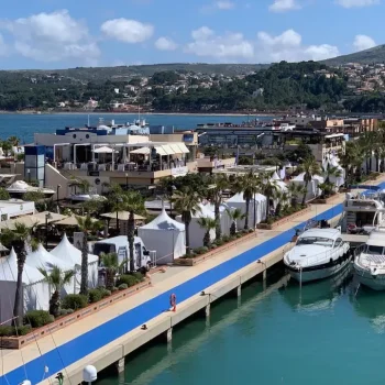 Vista de una marina con numerosos barcos y personas caminando por el muelle.