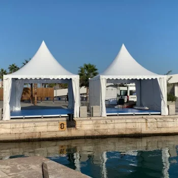 Dos carpas blancas están ubicadas frente al agua, formando parte de una feria al aire libre.