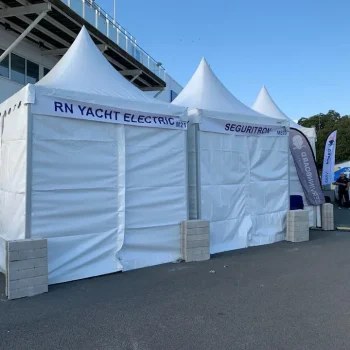 Carpa con toldo blanco y letrero "RN Yacht Electric" en el contexto de una feria.