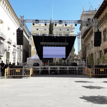 Escenario de feria ubicado en una plaza urbana, con luces y adornos que crean un ambiente festivo.
