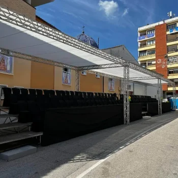Gradas con sillas bajo un toldo en un área urbana.