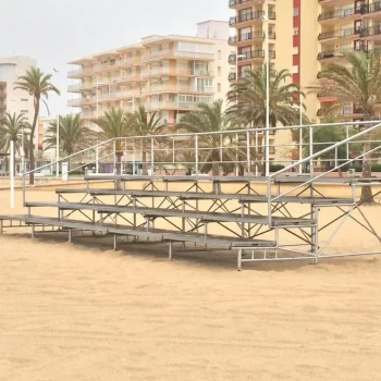 Gradas de metal en la playa, rodeadas de palmeras, ofreciendo un lugar para sentarse y disfrutar del paisaje.