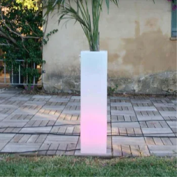 Macetero grande de resina con planta, iluminado por luces LED, creando un ambiente acogedor y moderno.