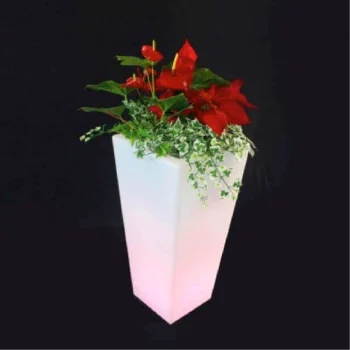 Macetero blanco de resina con flores rojas, iluminado con luz LED, creando un ambiente cálido y decorativo.