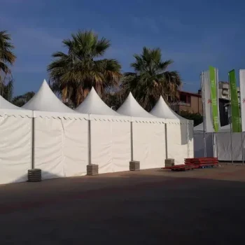 Tiendas blancas instaladas en una calle, rodeadas de palmeras, creando un ambiente festivo y acogedor.