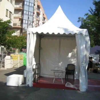 Carpa con mesa y sillas frente a un edificio, creando un espacio al aire libre para reuniones o eventos.