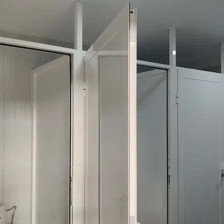Baño con dos puertas blancas y un inodoro visible en el interior.