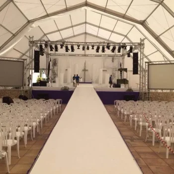 Ceremonia de boda en un gran toldo, con decoraciones elegantes y asientos dispuestos para los invitados.