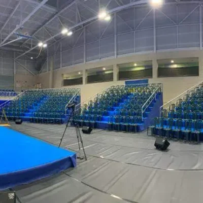 Auditorio amplio con sillas azules y un escenario al fondo, preparado para un evento o presentación.