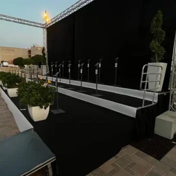 Escenario con cortinas negras y un soporte de micrófono en el centro, listo para una presentación.