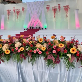 Escenario decorado con flores y adornos elegantes, creando un ambiente festivo.
