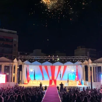 Escenario grande con una alfombra roja y fuegos artificiales iluminando el fondo.