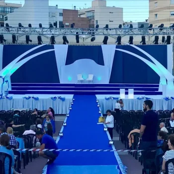 Escenario amplio con alfombra azul y sillas dispuestas para un evento o presentación.